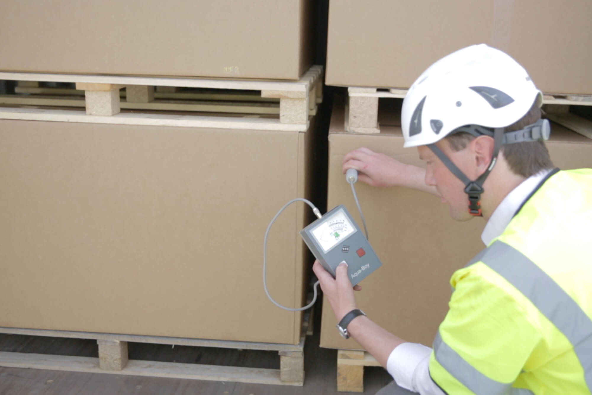 Man with a moisture measuring equipment analyzing some boxes