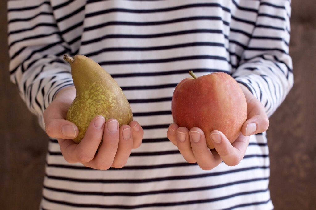 Person, die eine Birne und einen Apfel hält