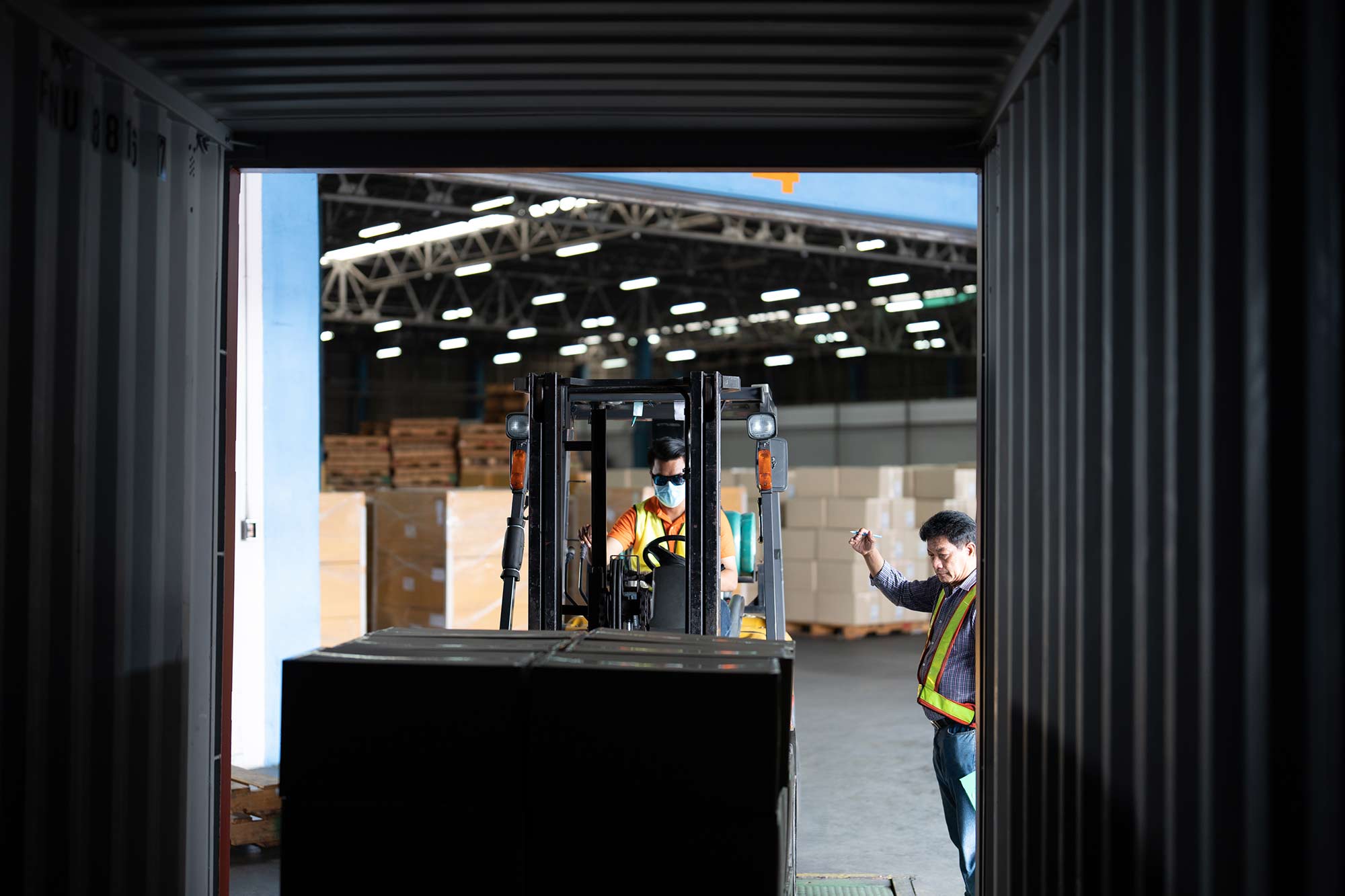 Workers beside an open 40-foot steel shipping container.