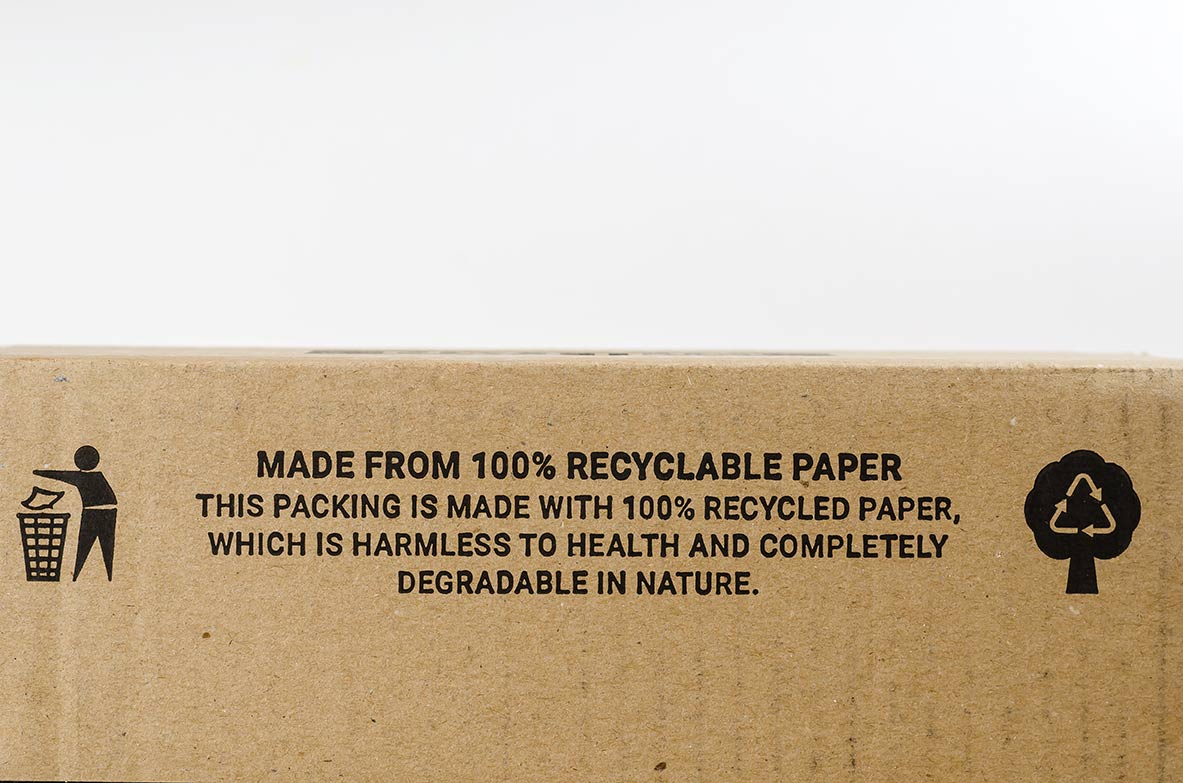 Emballage en carton recyclé arborant des icônes de durabilité imprimées et un message indiquant qu'il est fabriqué en papier 100 % recyclable.