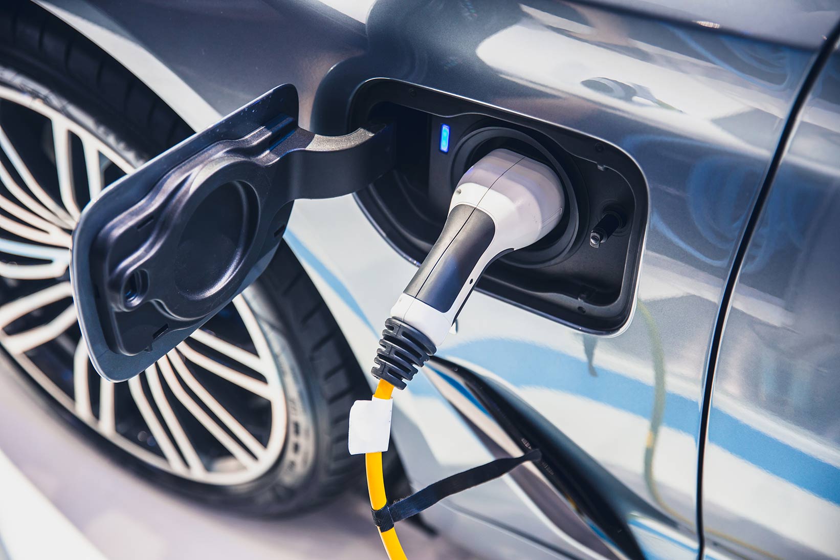 Nahaufnahme eines Ladekabels für ein Elektrofahrzeug, das an den Ladeanschluss eines Autos angeschlossen ist.