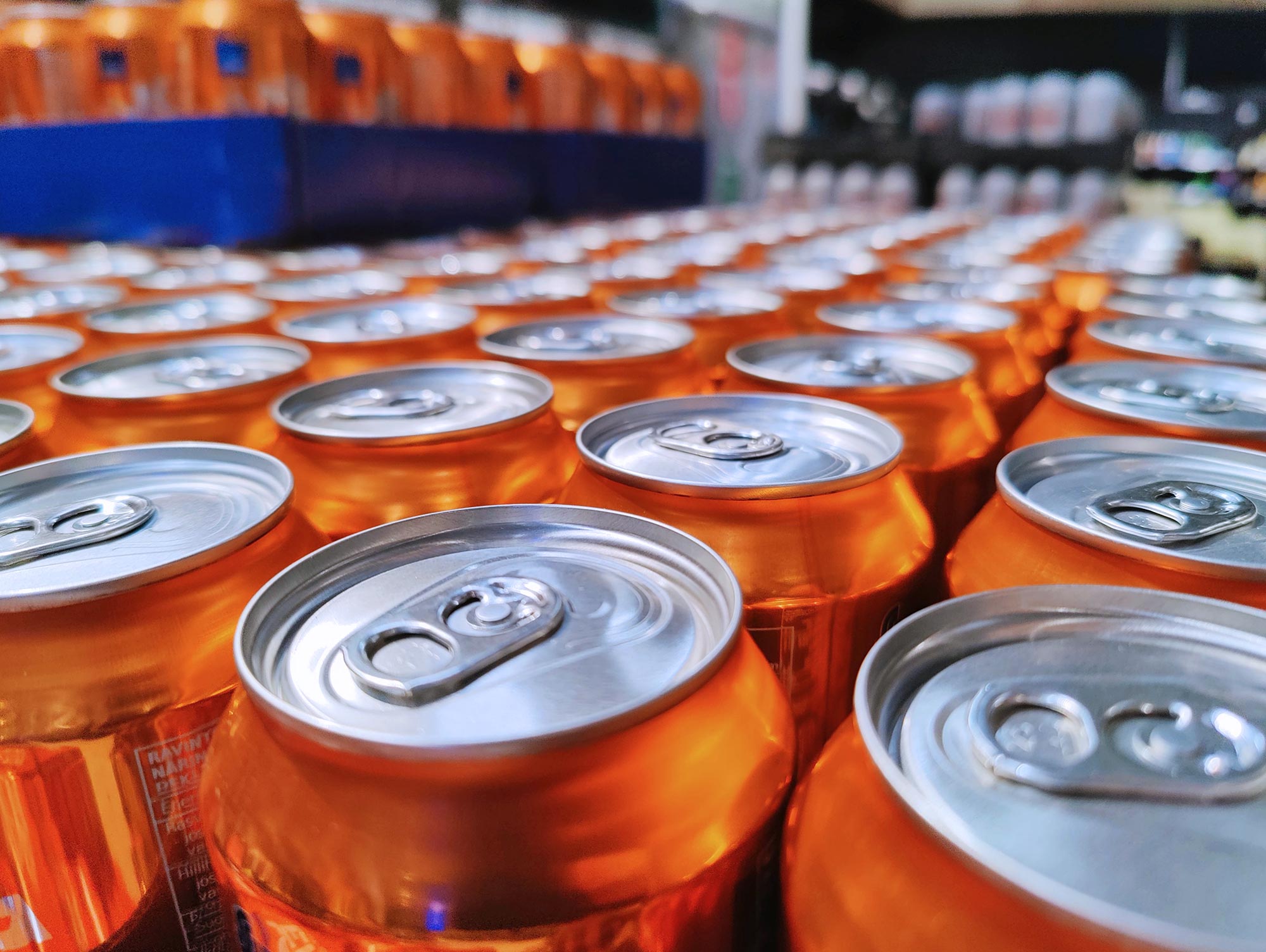 Close up shot of orange metallic cans in a beverage factory