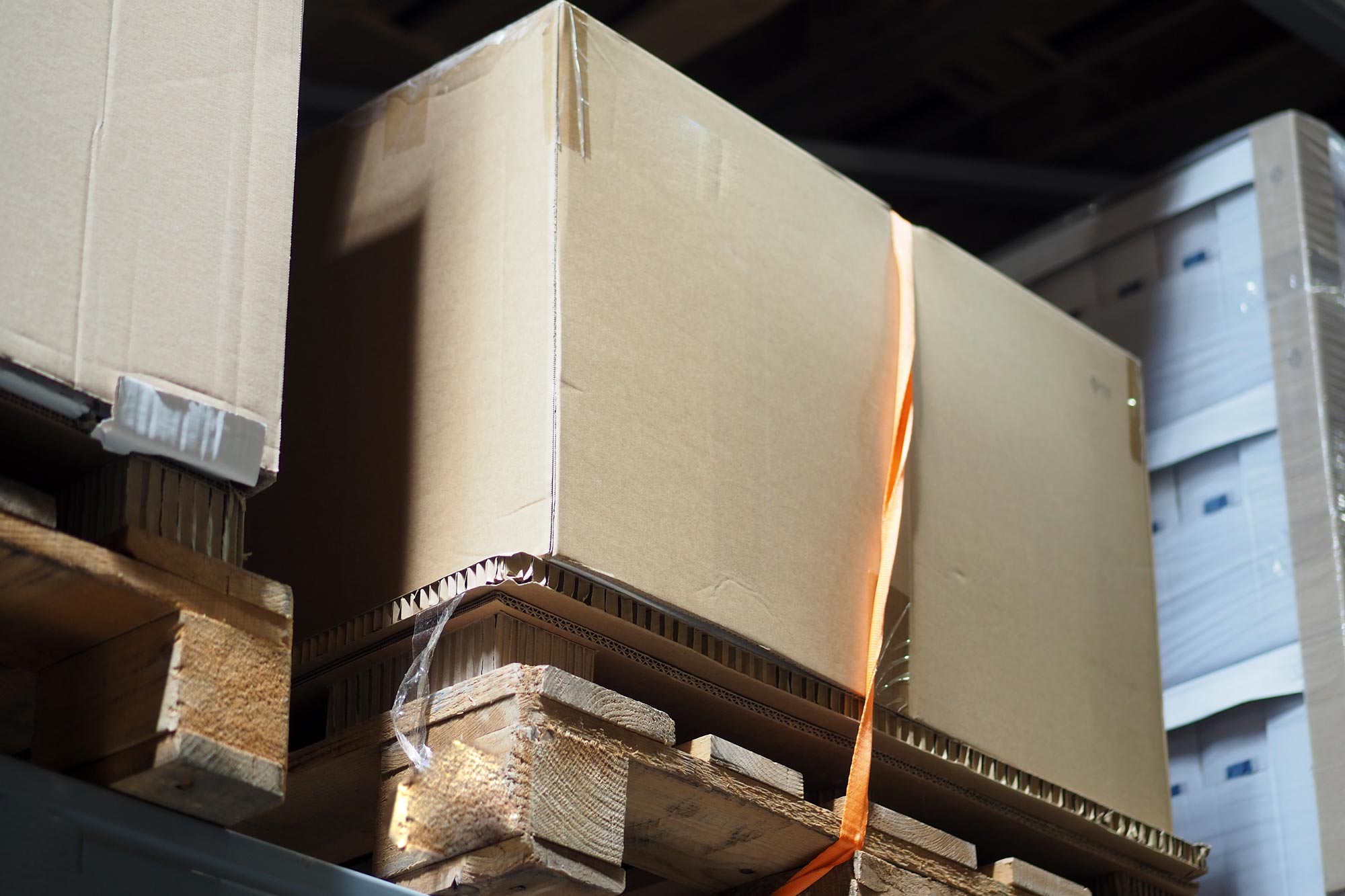 Cardboard boxes stacked on wooden pallets in a warehouse.
